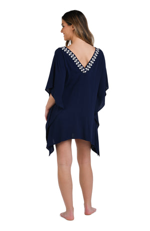 Model is wearing an indigo and white patterned tunic cover up that resembles a string of white sea scallop shells.