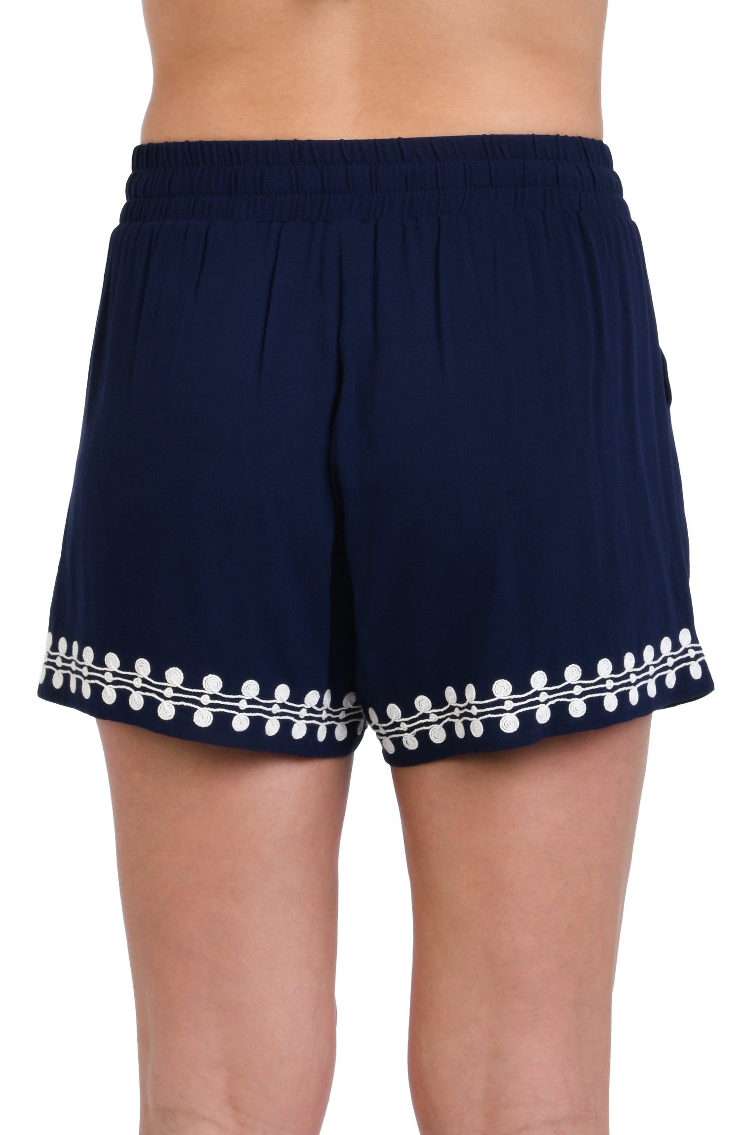 Model is wearing an indigo and white patterned beach shorts that resembles a string of white sea scallop shells.