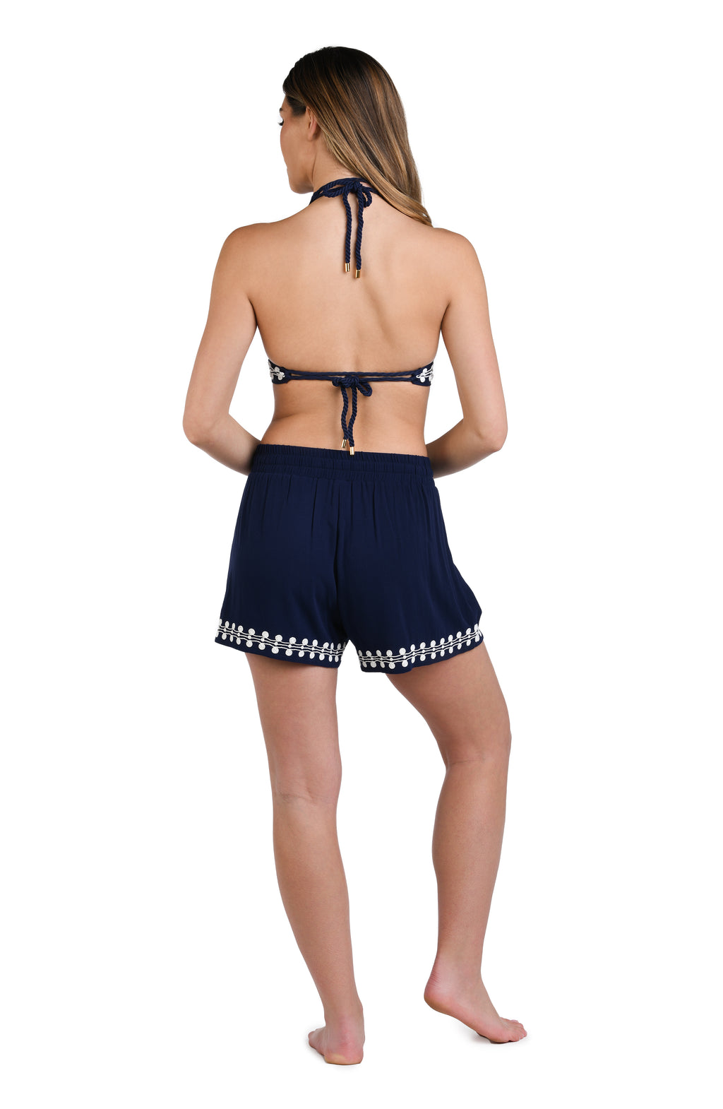 Model is wearing an indigo and white patterned beach shorts that resembles a string of white sea scallop shells.