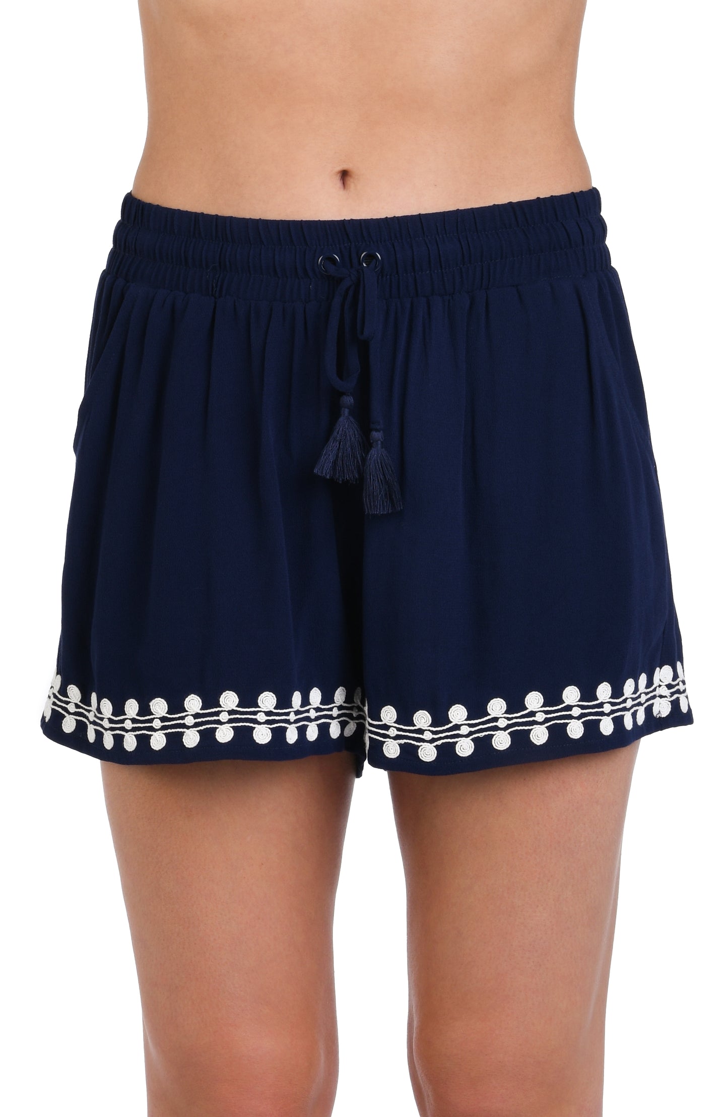 Model is wearing an indigo and white patterned beach shorts that resembles a string of white sea scallop shells.