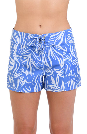 Model is wearing a two-toned board short bottom with bold white botanical motifs on a background of contrasting shades of blue.