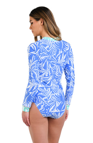 Model is wearing a two-toned rashguard with bold white botanical motifs on a background of contrasting shades of blue.