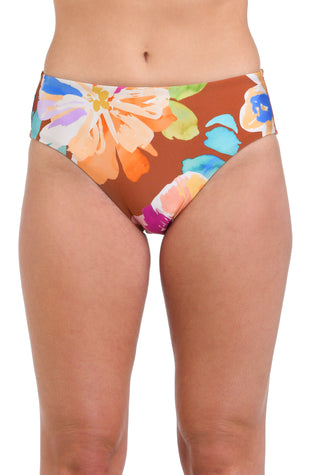 Model is wearing floral patterned swimsuit bottom with bold strokes of peach, pink, orange, and blue hues on a rich brown background.