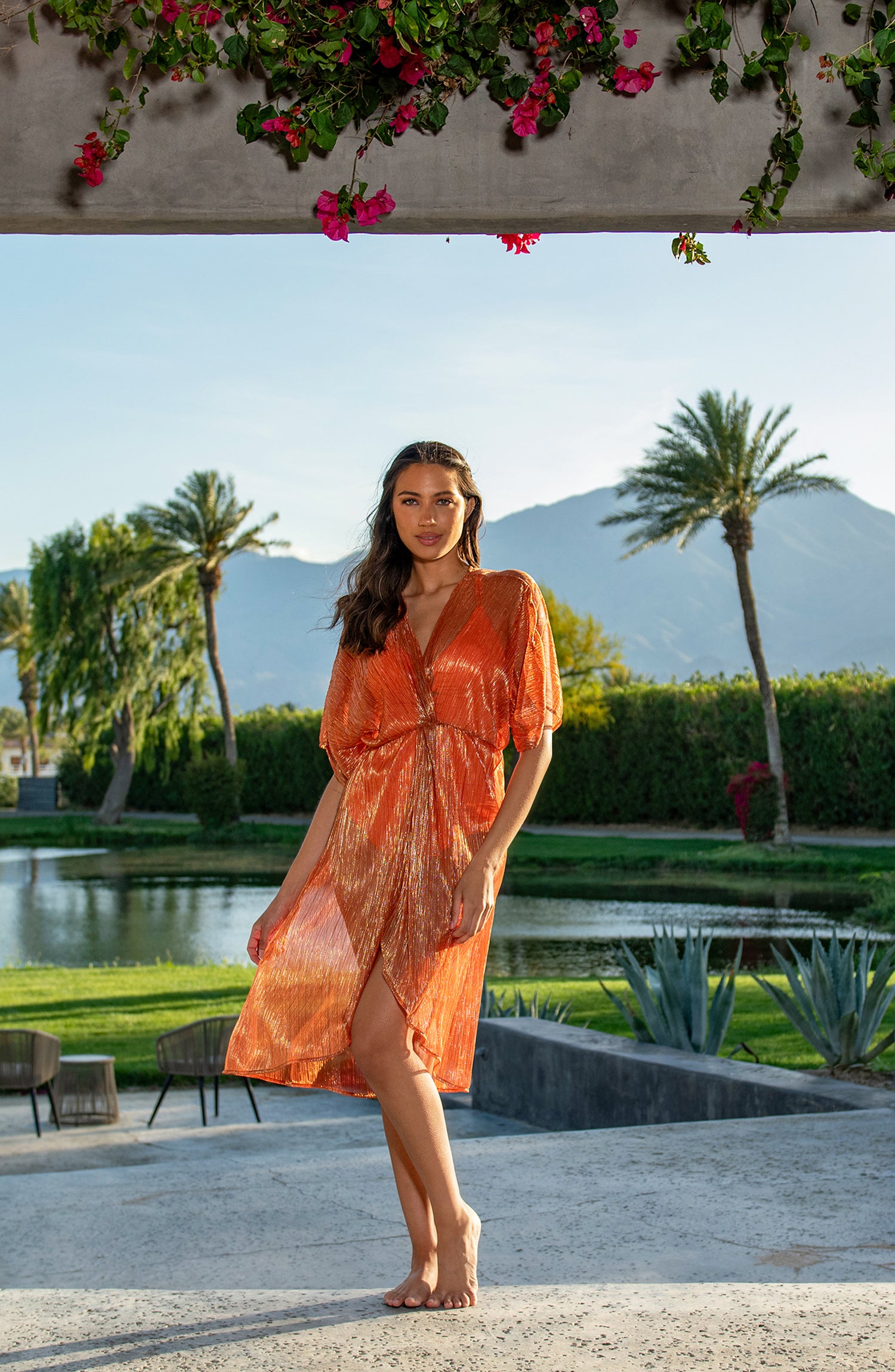 Model is wearing a shimmering orange and pink short sleeve midi dress cover up.