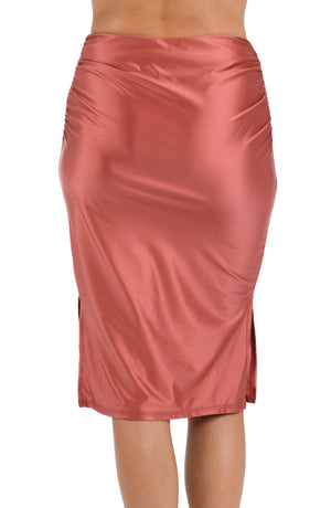 This is a back image of a model wearing a sienna colored shirred mid-length cover up skirt with side slits from the Earth Goddess swim collection.