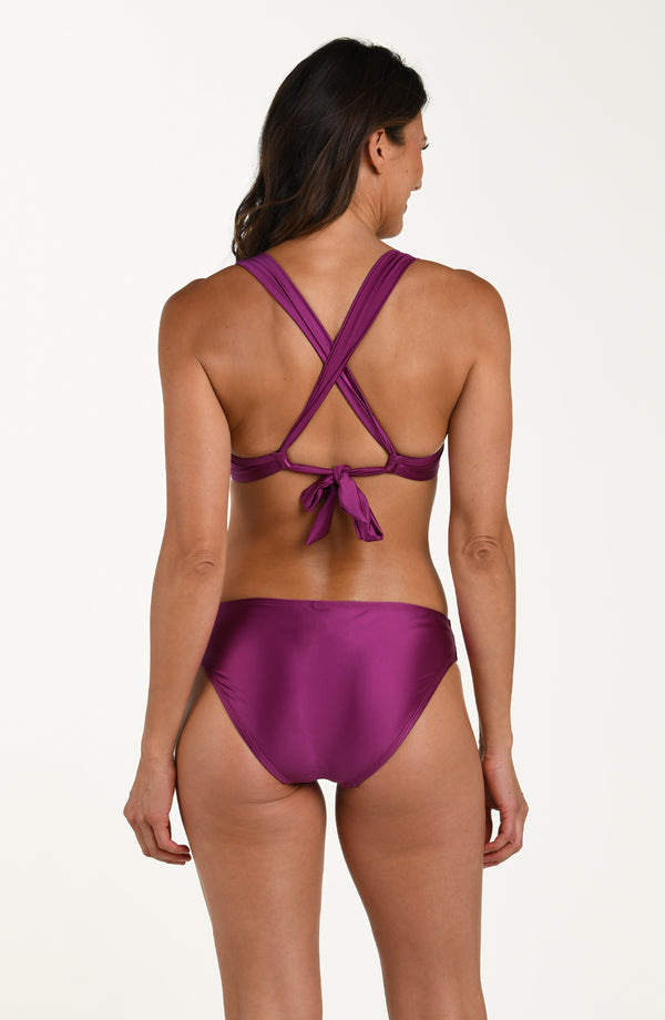 Back image of model wearing basic hipster bikini bottoms in a berry color. 