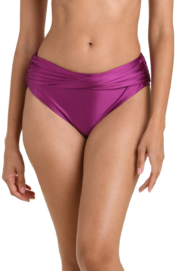 Front image of model wearing a berry colored bikini bottom with a mid-rise fit and a flattering crossover waistband design.