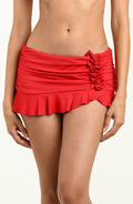 Red ruched swim skirt worn by a person on a plain background