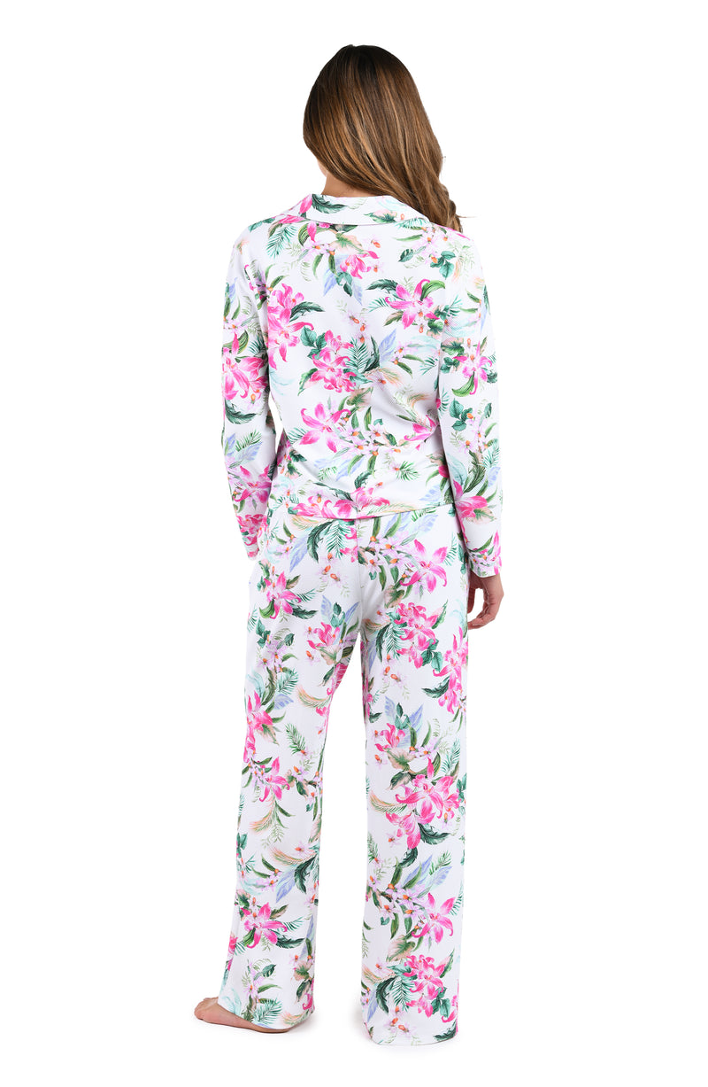 Model is wearing a white, pink, and green multicolored tropical printed long sleeve shirt and pant pajama set. 