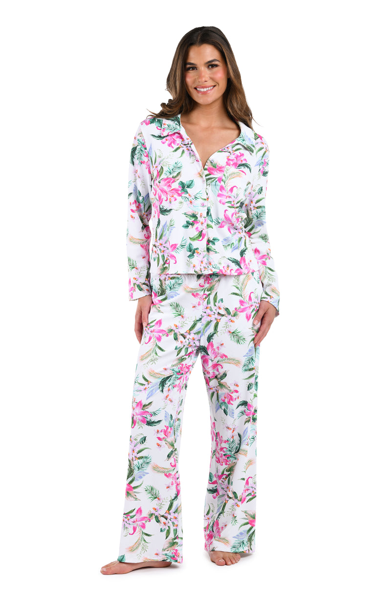 Model is wearing a white, pink, and green multicolored tropical printed long sleeve shirt and pant pajama set. 