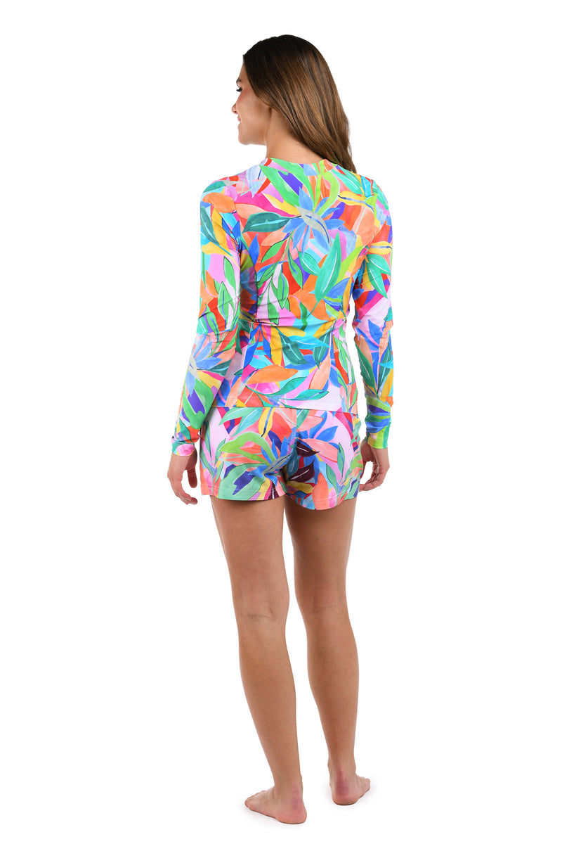 Back image of model wearing the Tropi-flage Half Zip Rashguard in a bright multi colored tropical print.