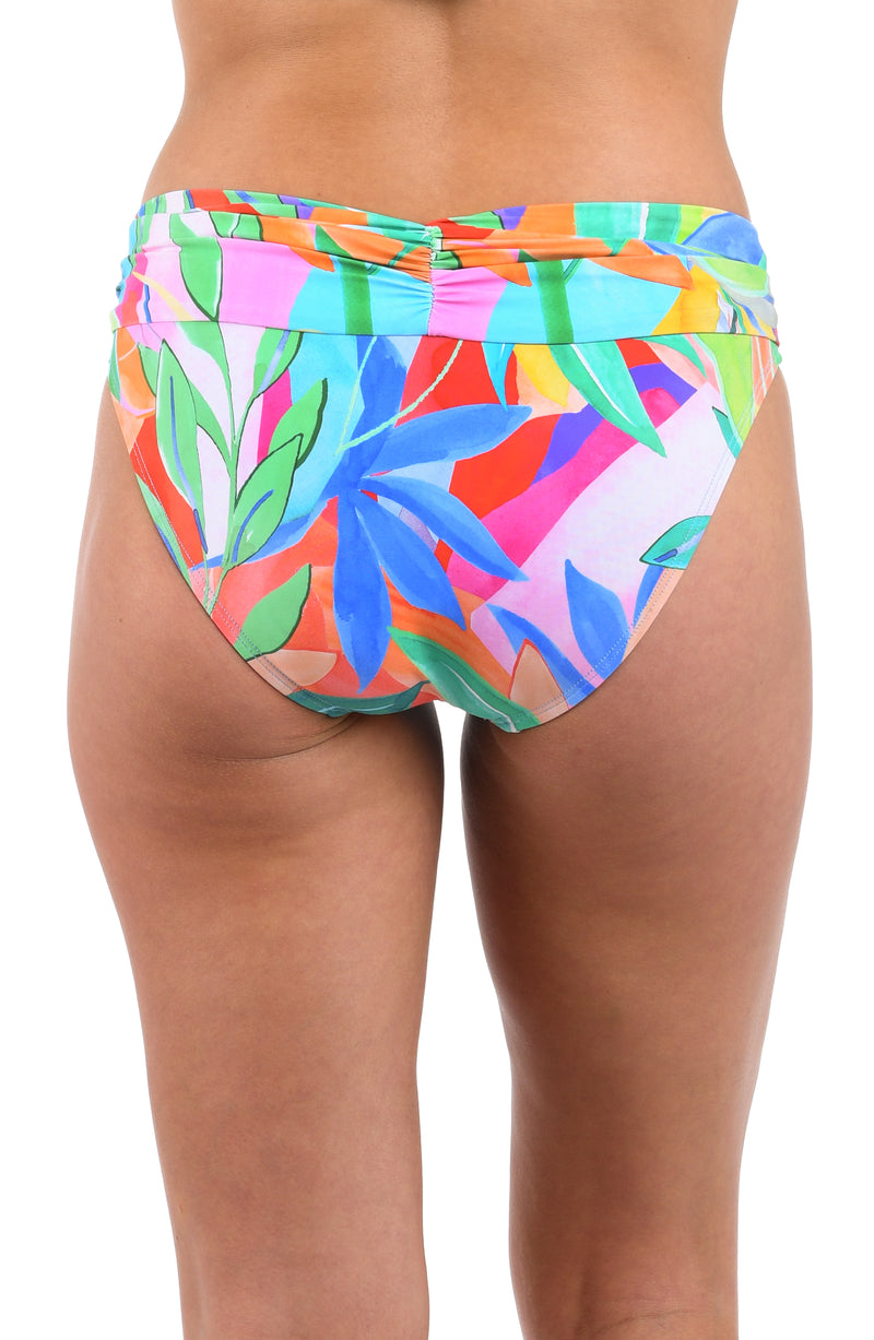 Back image of model wearing the Tropi-flage Shirred Band Hipster Bottom in a bright multi colored tropical print.