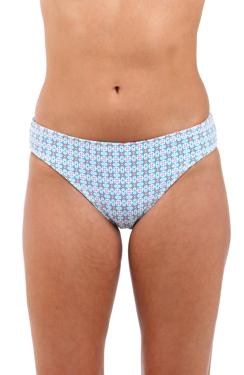 Reverse front image of model wearing the Riviera Resort Reversible Hipster Bottom in a light blue multi colored geometric print.