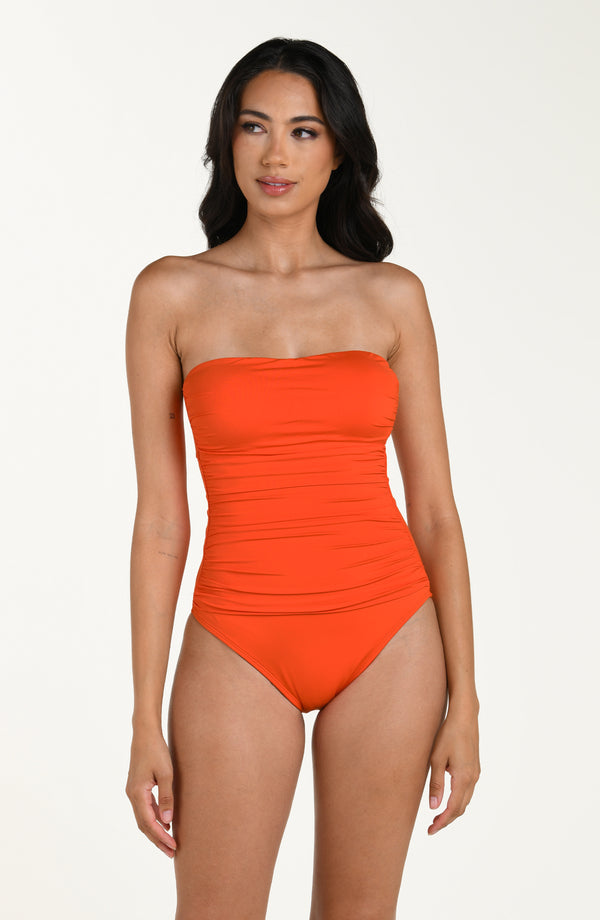 Front image of model wearing a solid tangelo (orange) colored one-piece swimsuit with shoulder straps removed, a straight neckline, and ruched detailing at the waist.