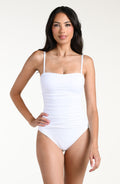 Woman wearing a white bandeau one piece swimsuit against a plain background