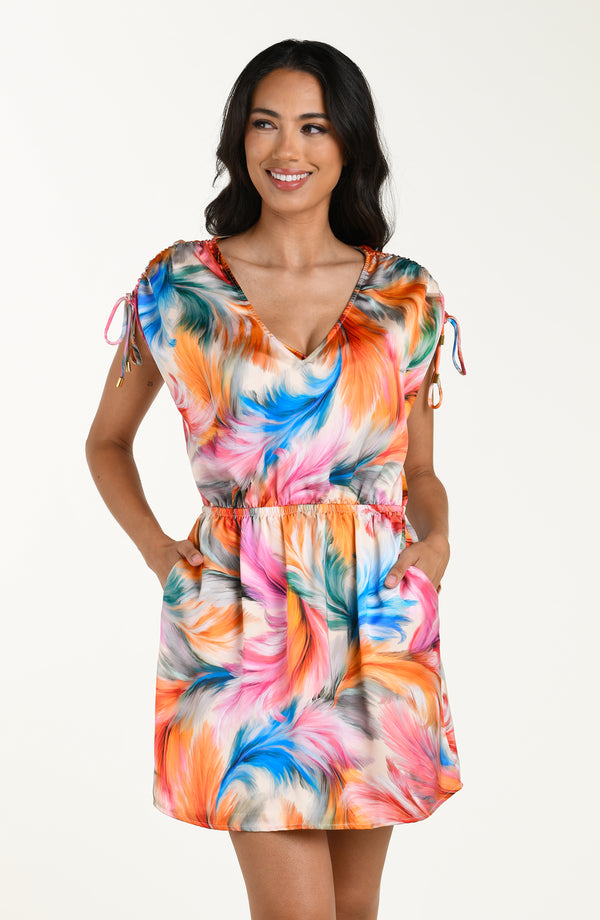Front image of model wearing a multicolored feather printed short cover-up dress featuring a V-neckline, cinched waist, and adjustable drawstring sleeves, and pockets.