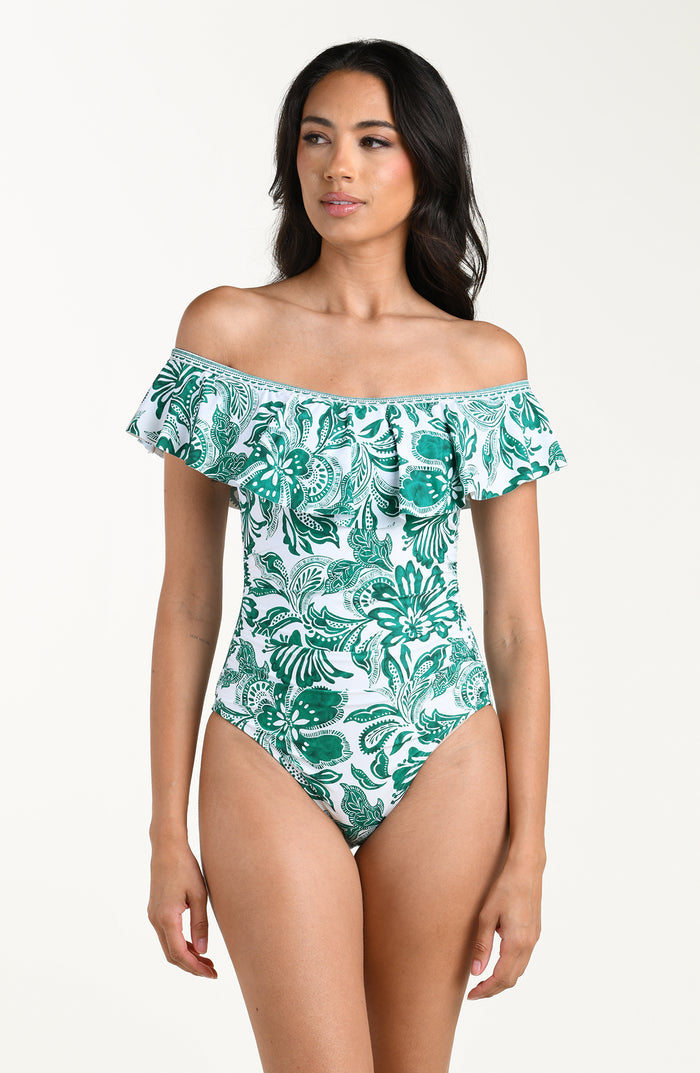 Woman wearing a green floral off-shoulder swimsuit on a white background