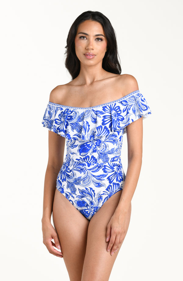 Woman wearing a blue and white floral off-shoulder swimsuit on a white background