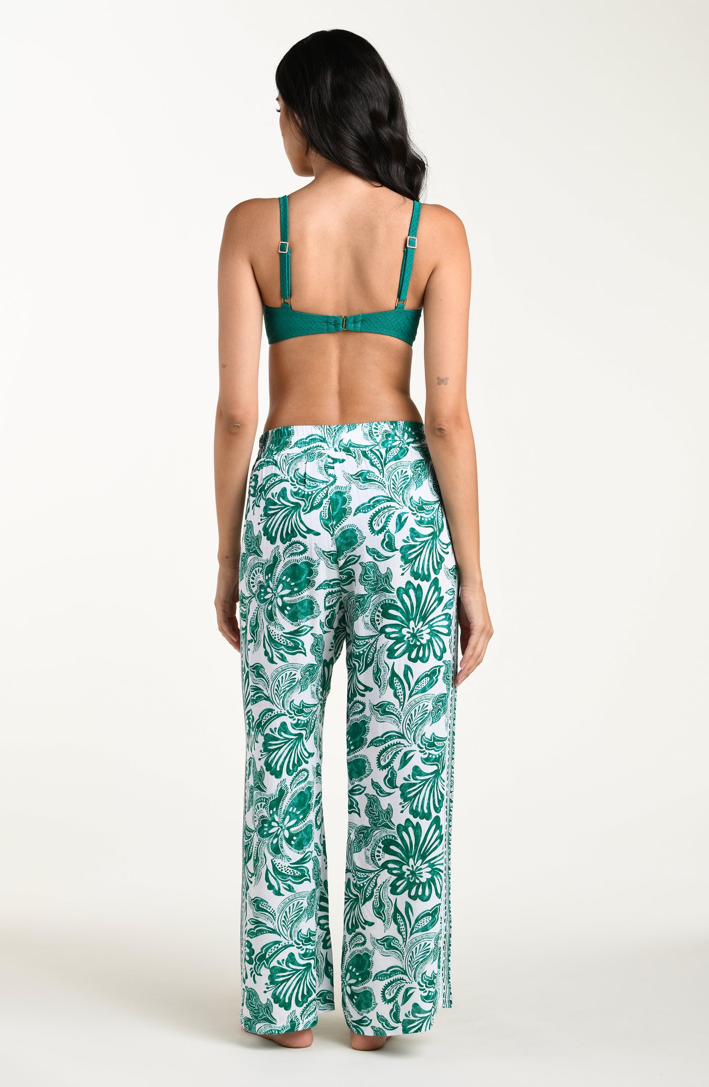 
                  
                    Woman wearing a green bikini top and leaf-patterned pants on a white background
                  
                