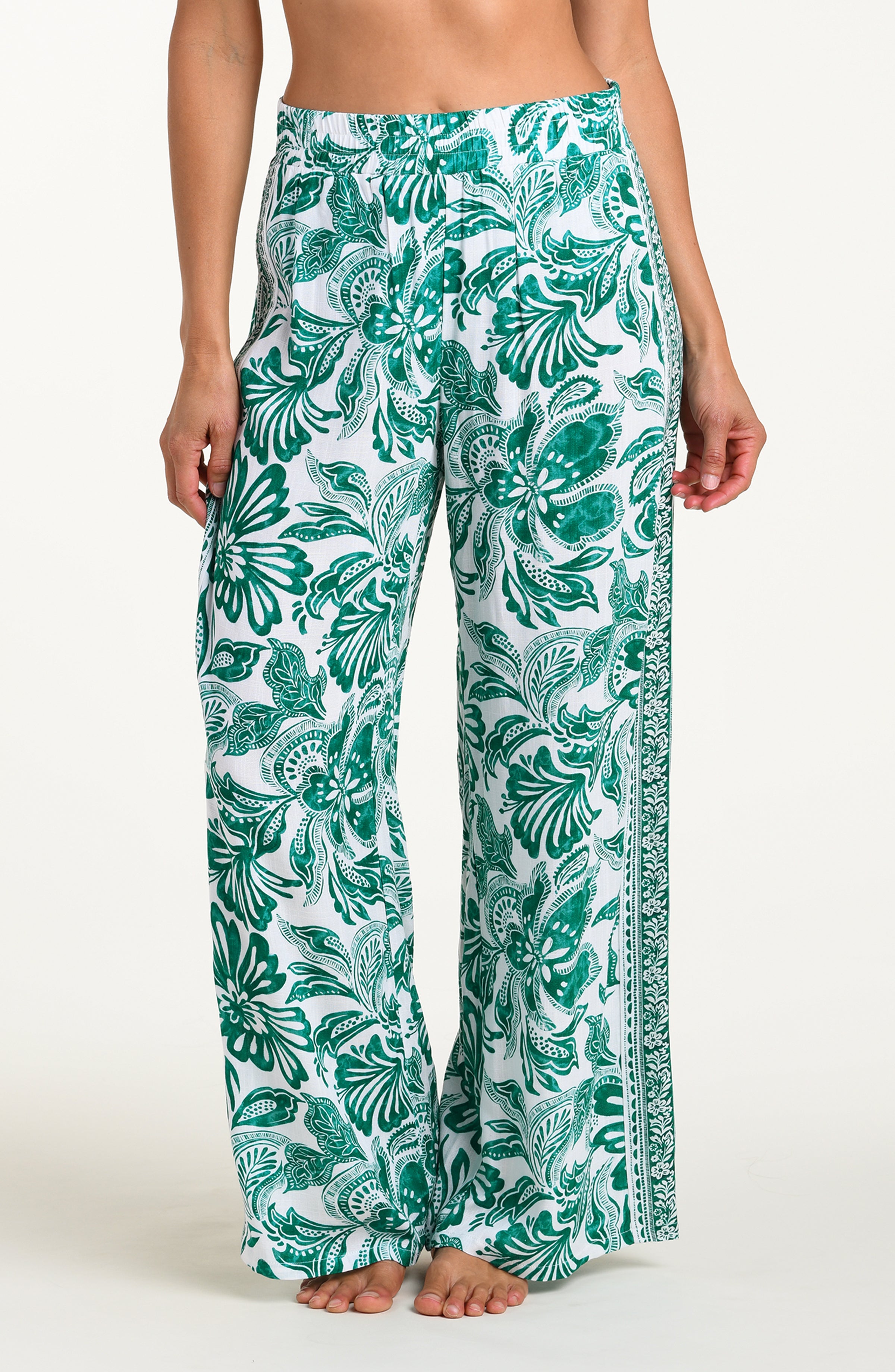 Green and white floral-patterned pants on a white background