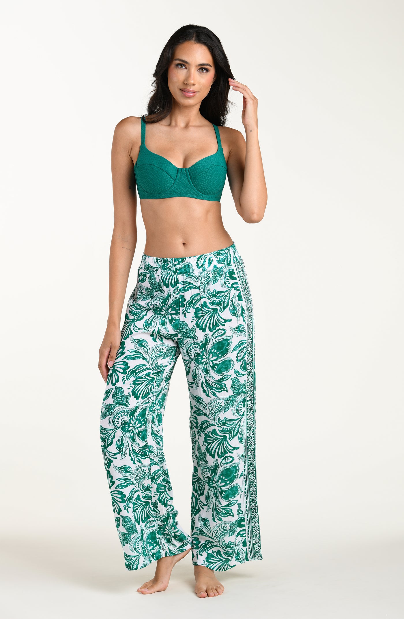 
                  
                    Woman wearing a green bikini top and leaf-patterned pants on a white background
                  
                