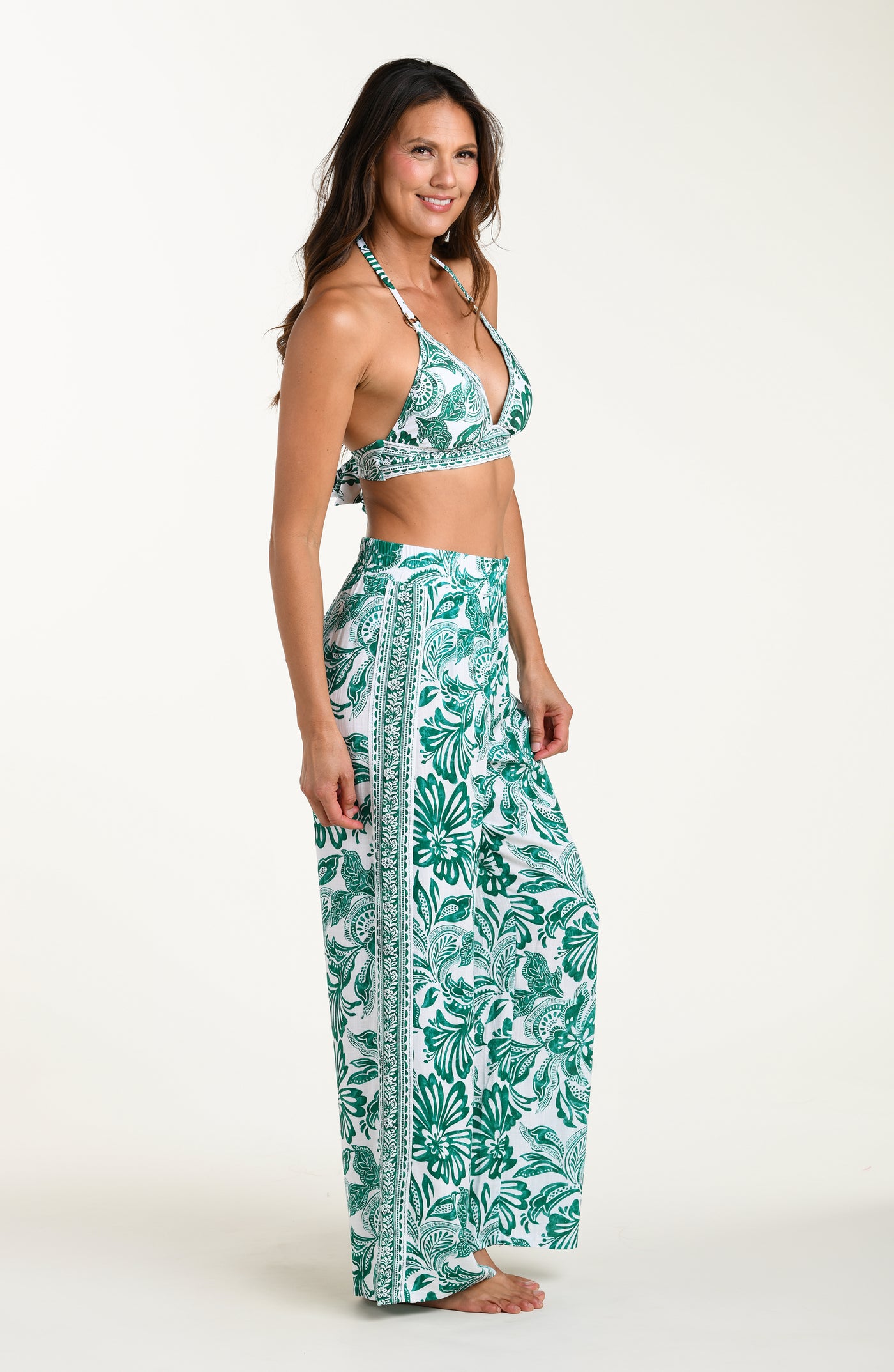 
                  
                    Woman wearing a green bikini top and leaf-patterned pants on a white background
                  
                