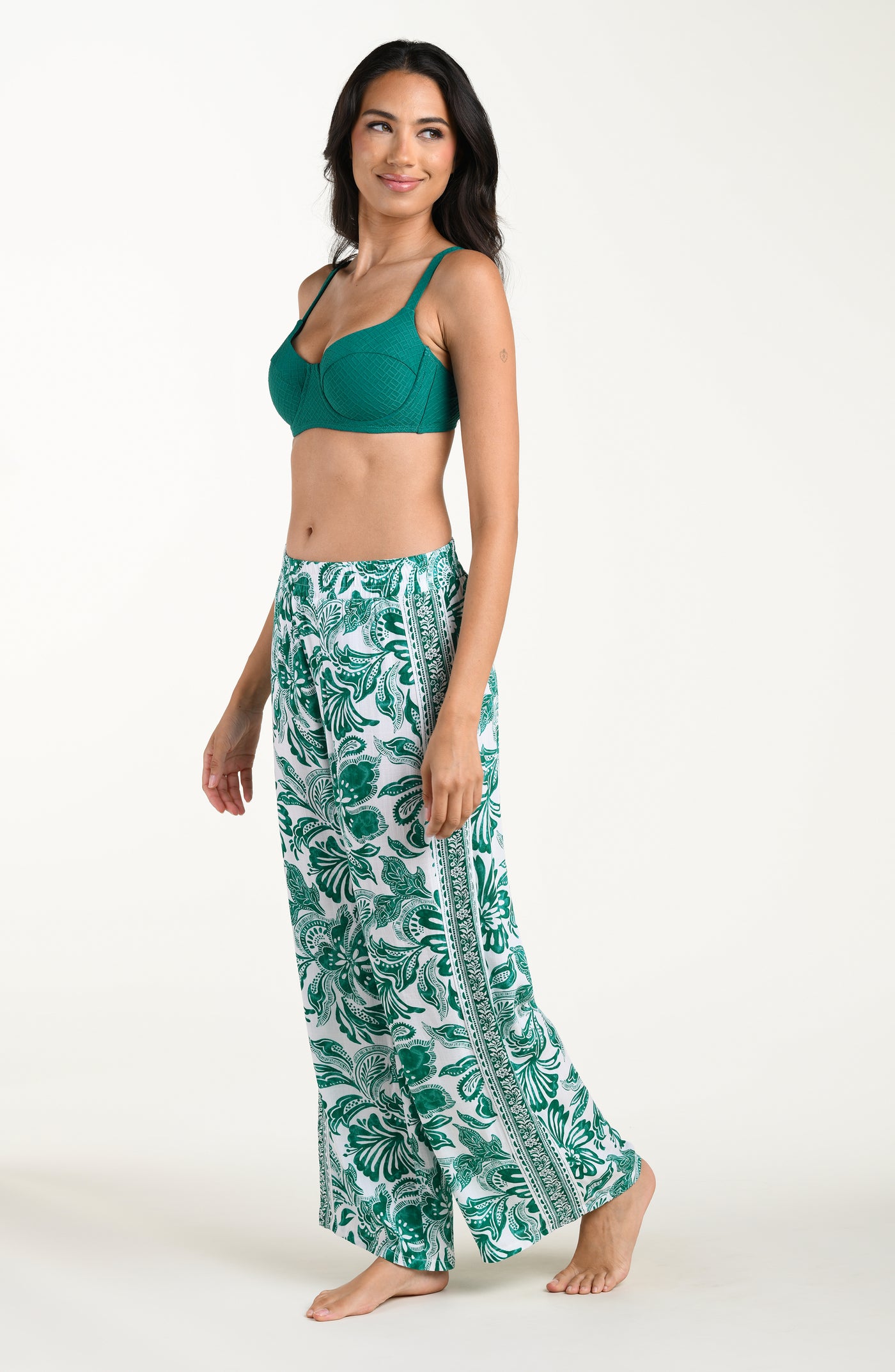 
                  
                    Woman wearing a green bikini top and leaf-patterned pants on a white background
                  
                