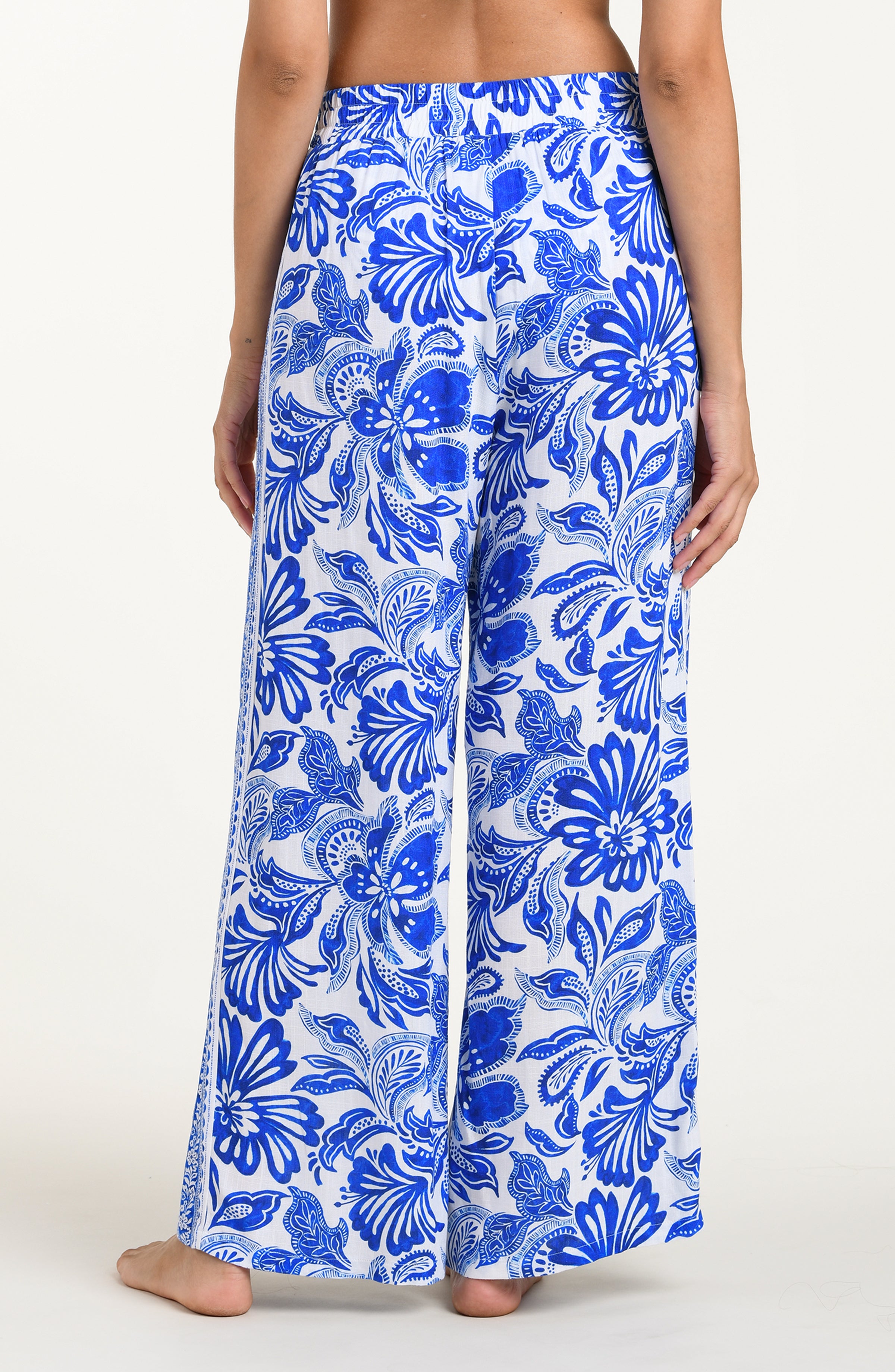 Person wearing blue floral patterned pants on a white background