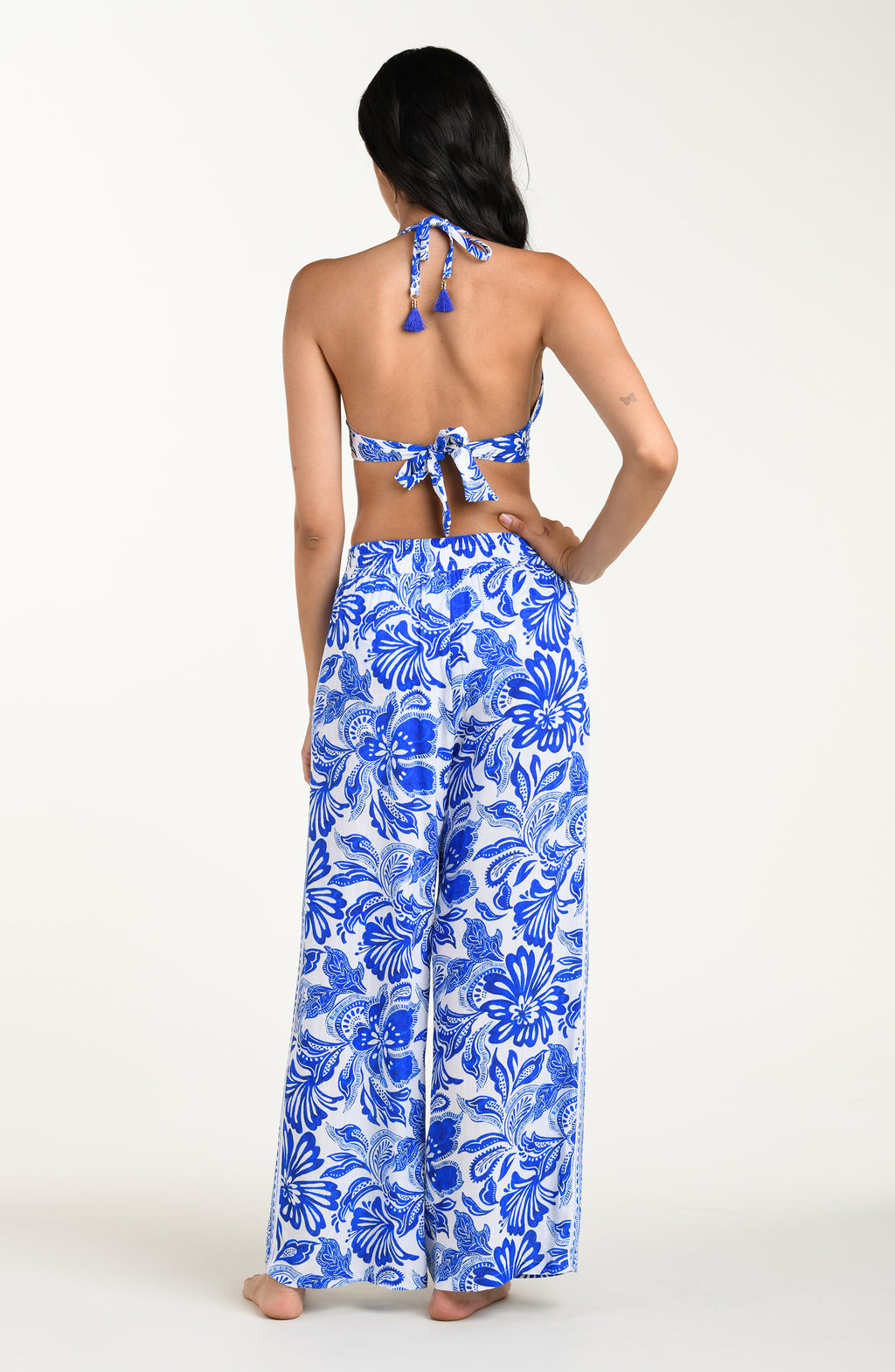 Woman wearing a blue floral bikini top and wide-leg pants on a white background