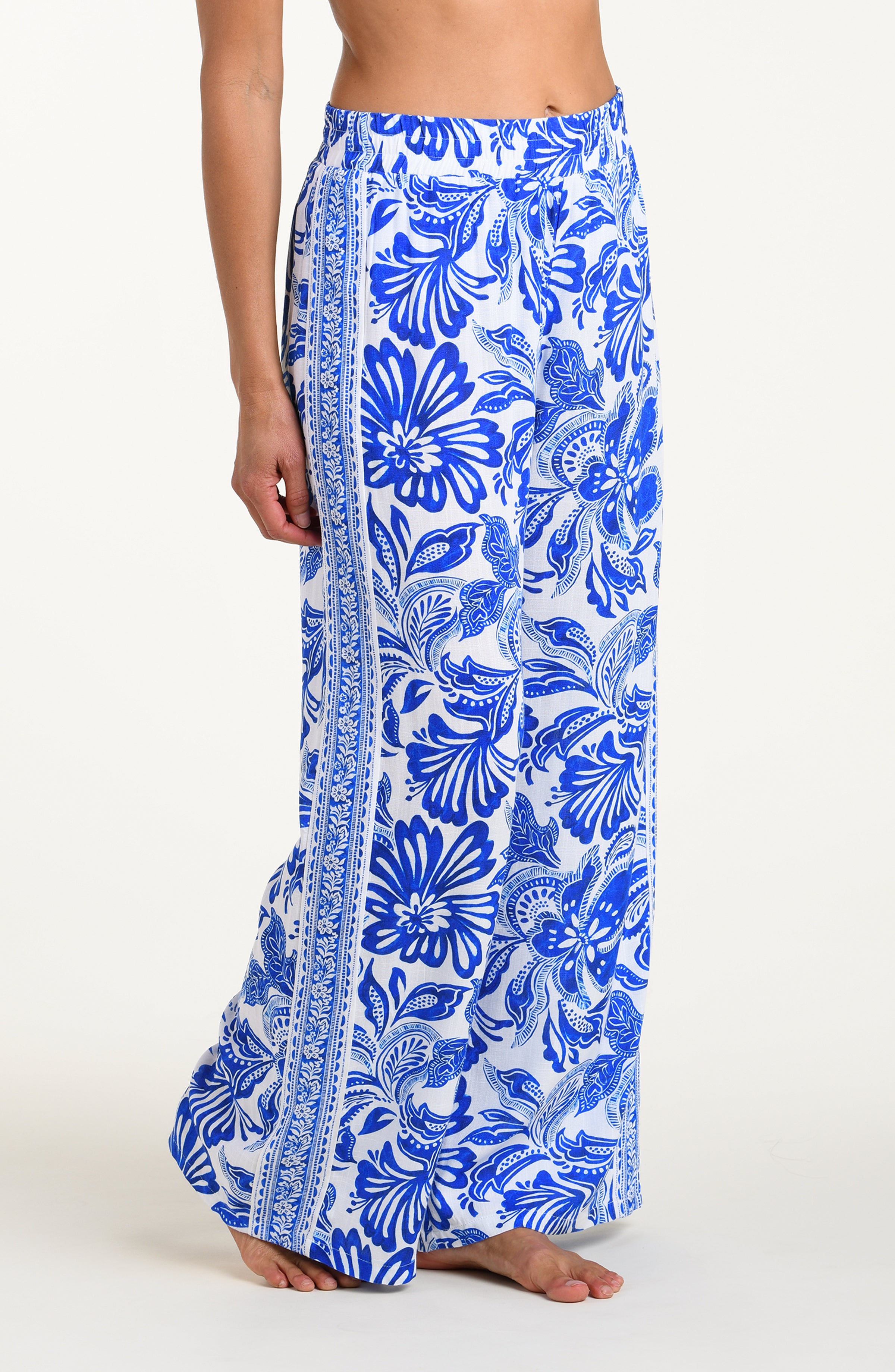 Person wearing blue floral patterned pants on a white background