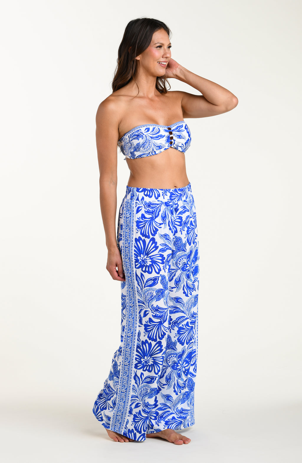 Woman wearing a blue floral strapless top and long skirt on a white background
