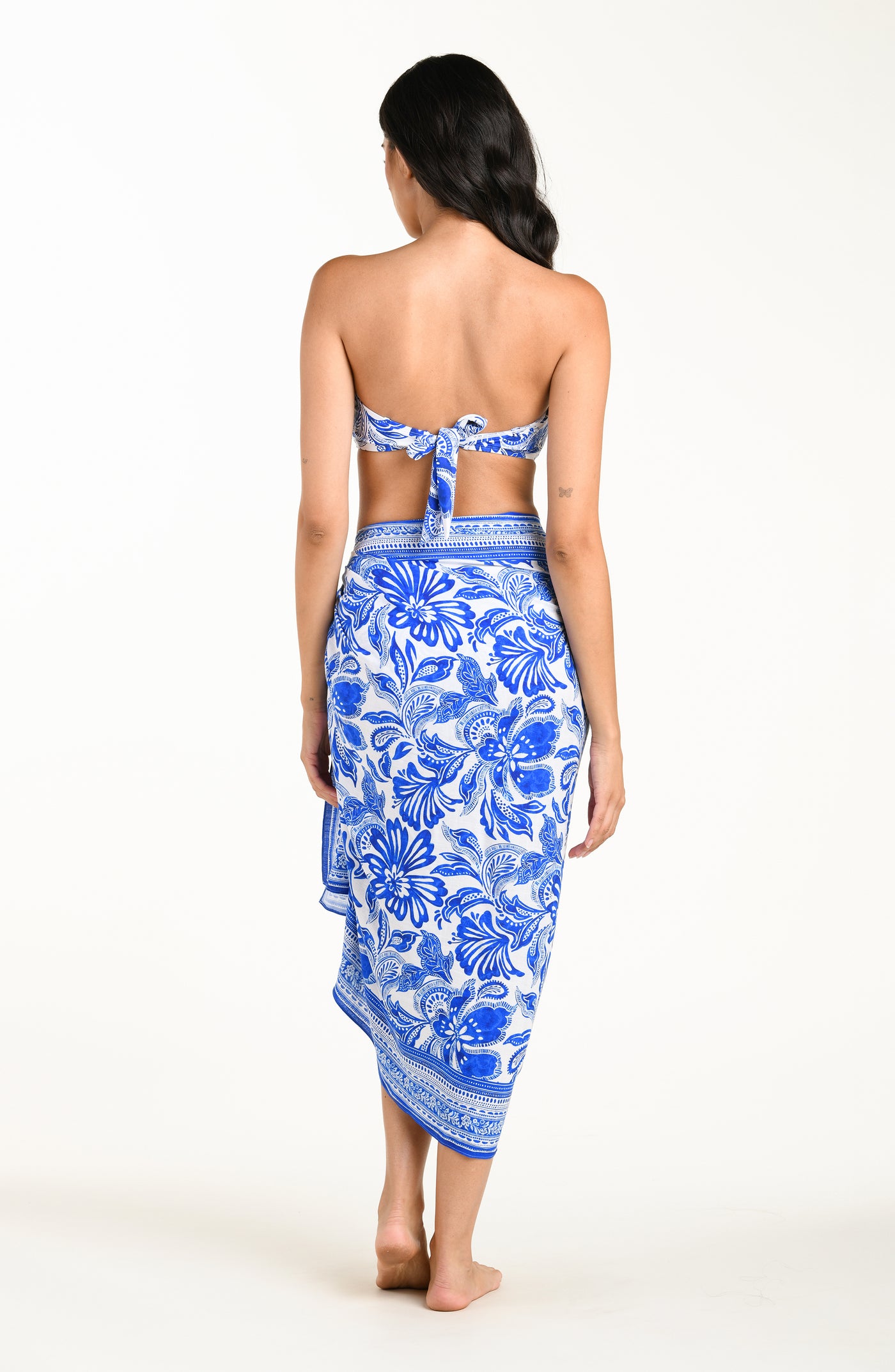 
                  
                    Woman wearing a blue floral patterned bikini top and matching sarong on a white background
                  
                