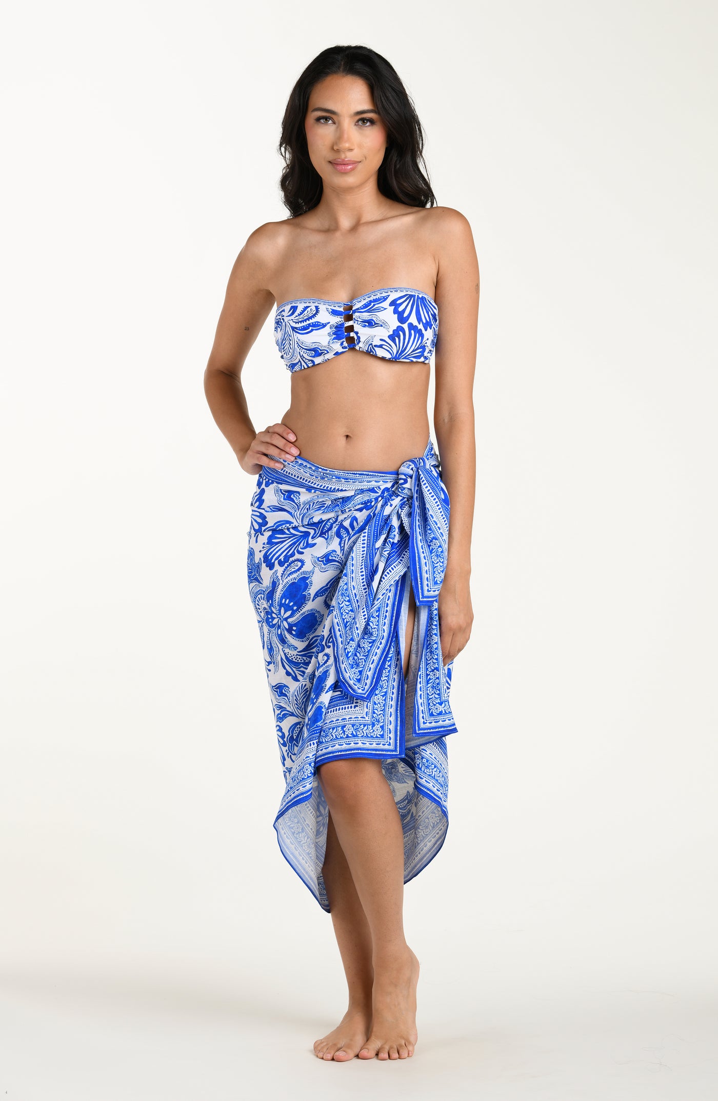
                  
                    Woman wearing a blue floral patterned bikini top and matching sarong on a white background
                  
                