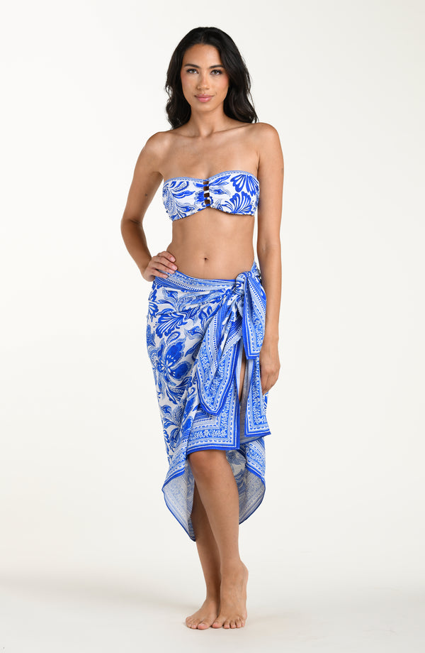 Woman wearing a blue floral patterned bikini top and matching sarong on a white background