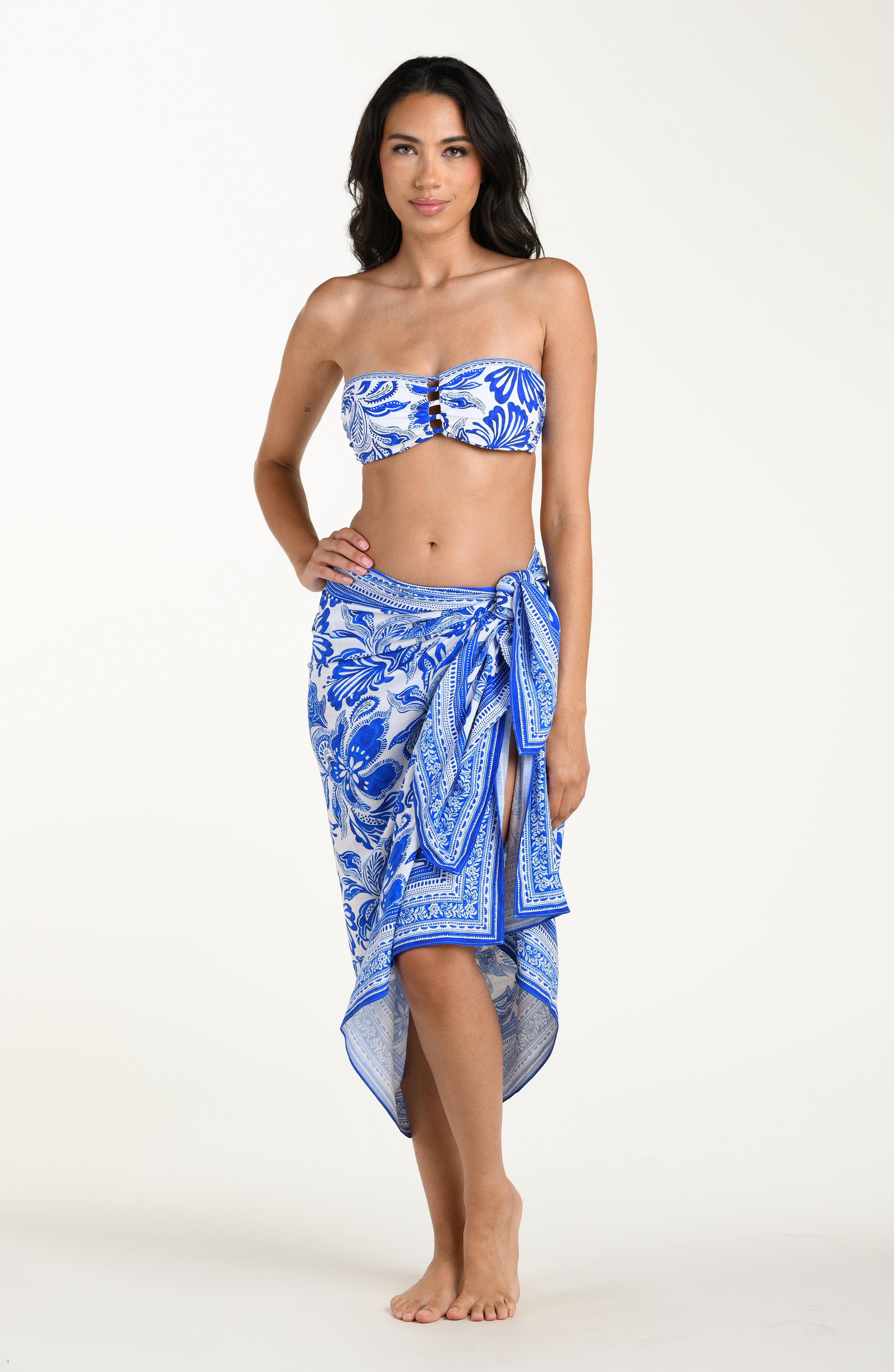 Woman wearing a blue floral patterned bikini top and matching sarong on a white background