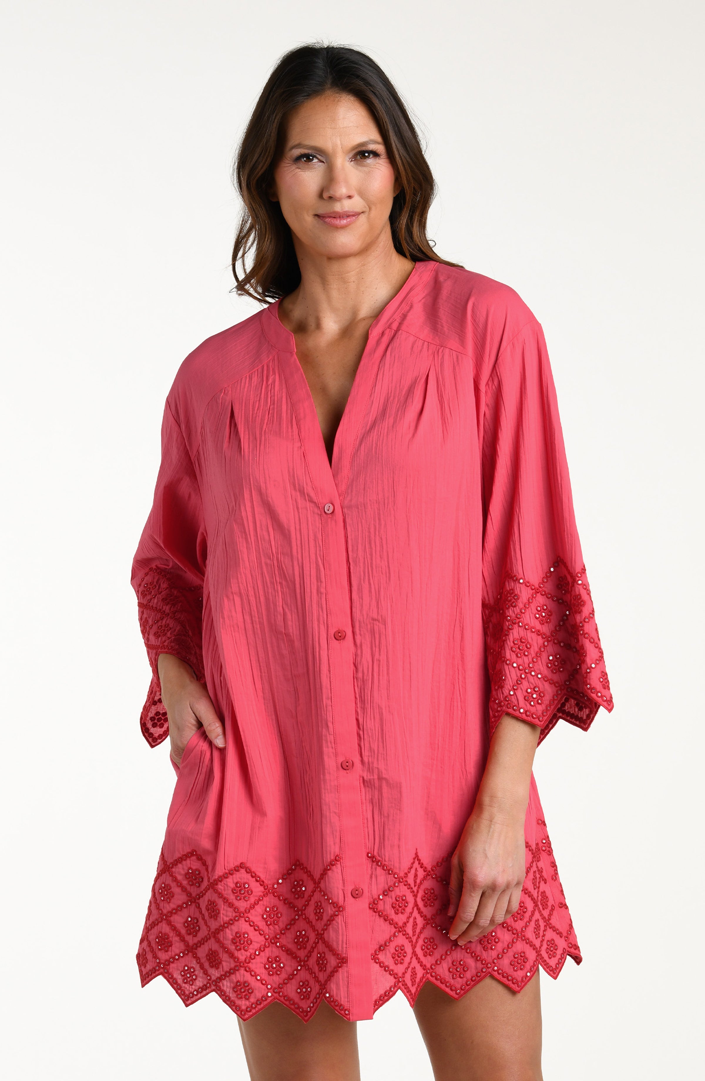 Woman wearing a guava colored V-neck tunic against a white background. 