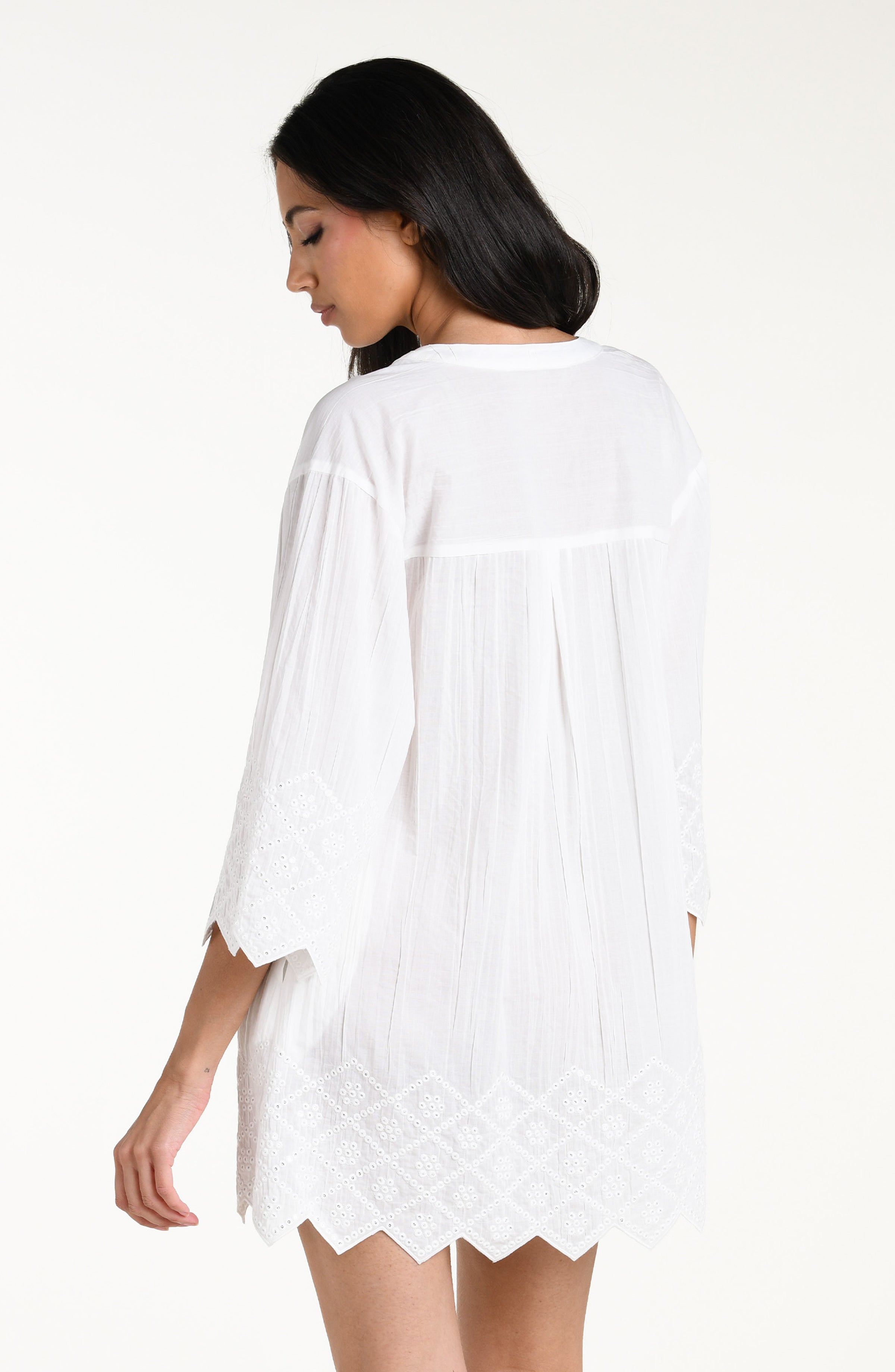Woman wearing a white V-neck tunic against a white background