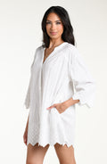 Woman wearing a white V-neck tunic against a white background