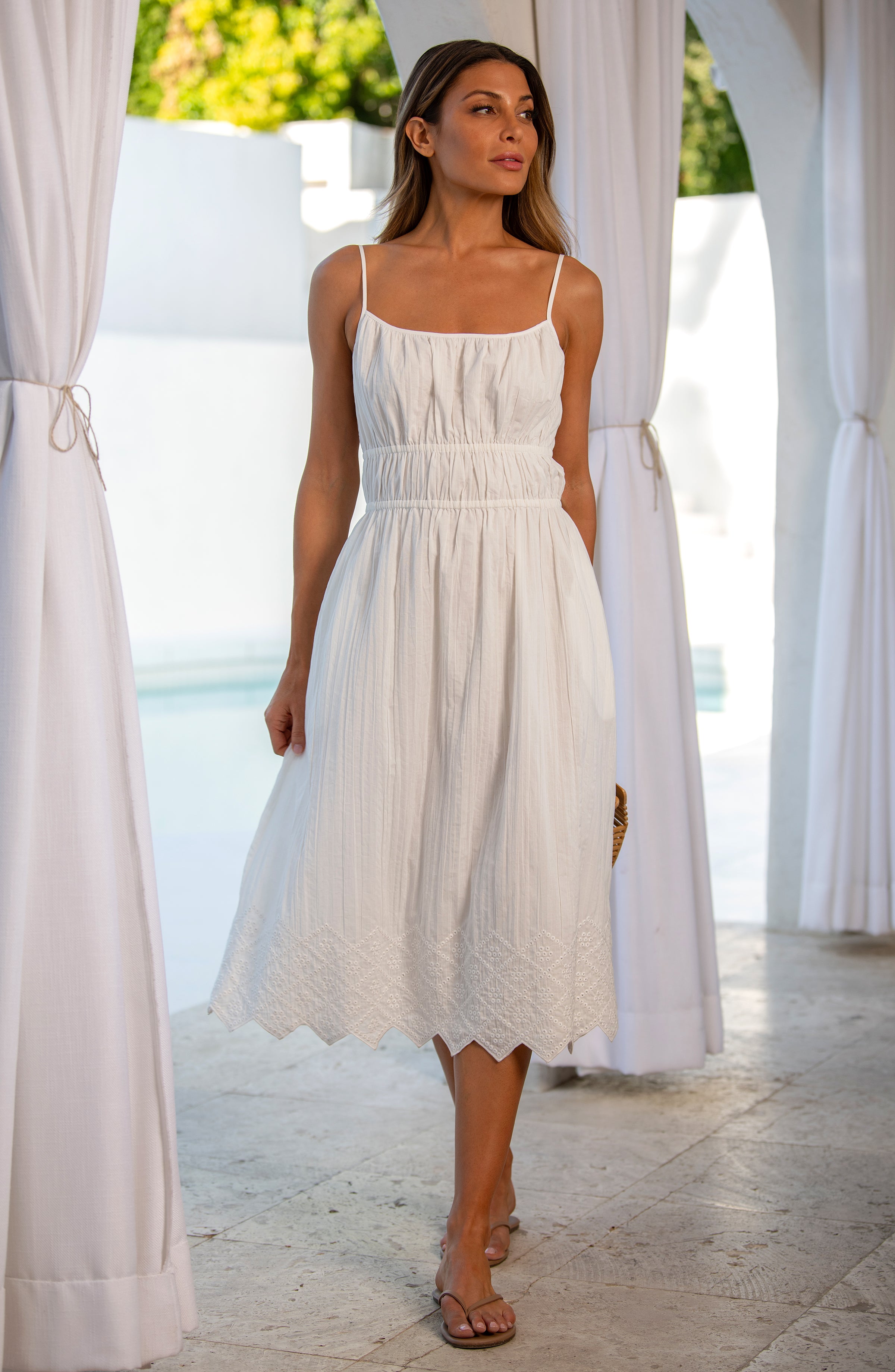Woman wearing a white midi dress standing outdoors.