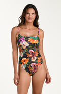 Front image of model wearing a multicolored tropical printed one-piece swimsuit with thin shoulder straps, a straight neckline, and ruched detailing at the waist.