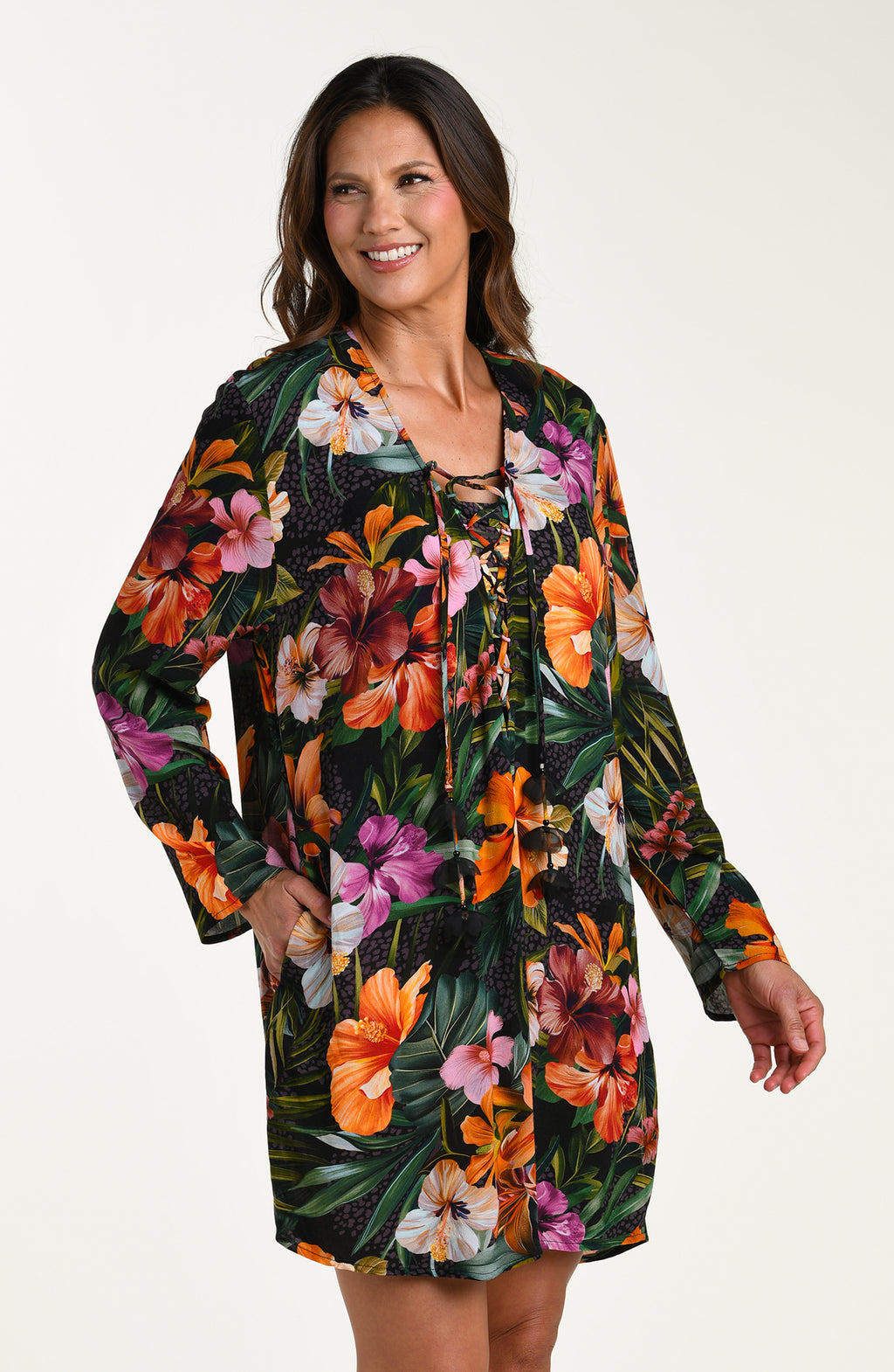 Side image of model wearing a multicolored tropical printed tunic cover-up featuring a loose, breezy fit with long sleeves and a lace-up neckline for effortless comfort and style.