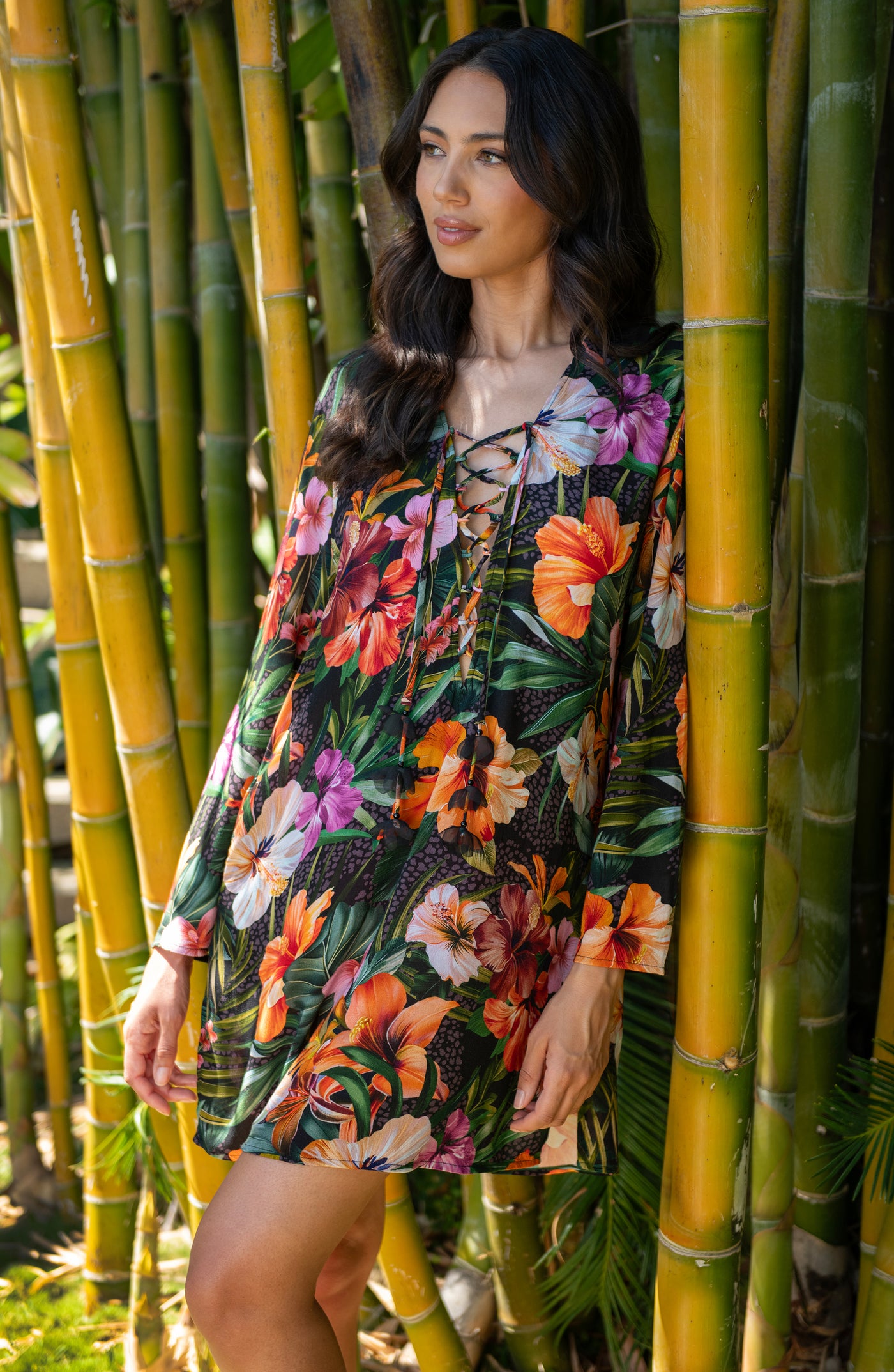 
                  
                    Lifestyle image of model wearing a multicolored tropical printed tunic cover-up featuring a loose, breezy fit with long sleeves and a lace-up neckline for effortless comfort and style.
                  
                