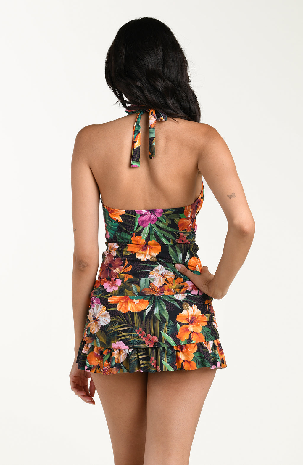 Back image of model wearing a multicolored tropical printed halter-neck tankini top with a tie closure at the back of the neck and a straight back design. This is paired with matching swim skirt bottom.