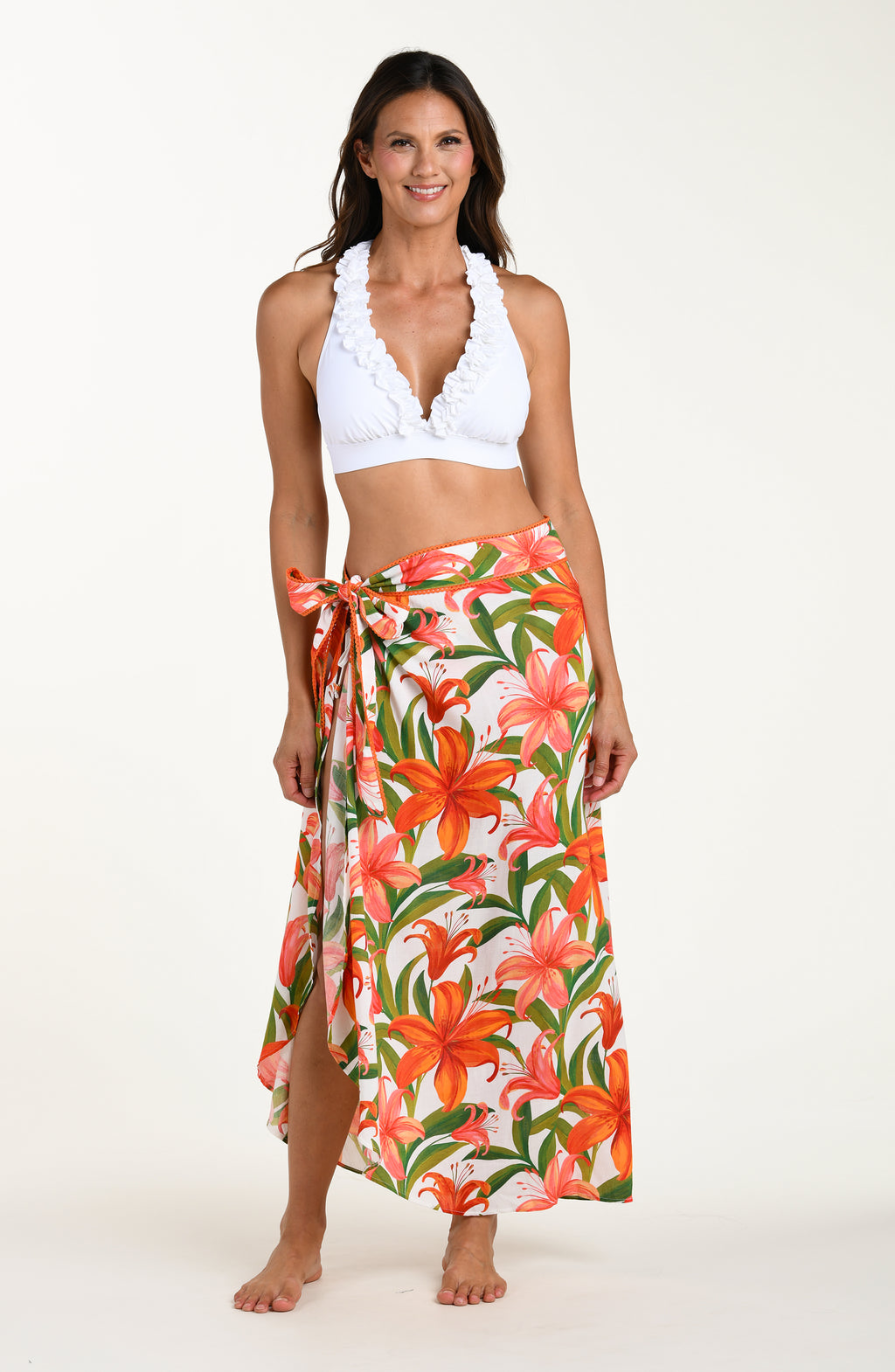 Woman wearing a swimsuit top and floral skirt on a white background