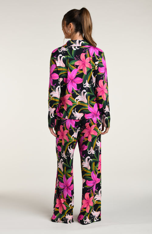 Woman wearing a colorful tropical long sleeve and pant pajama set against a white background.