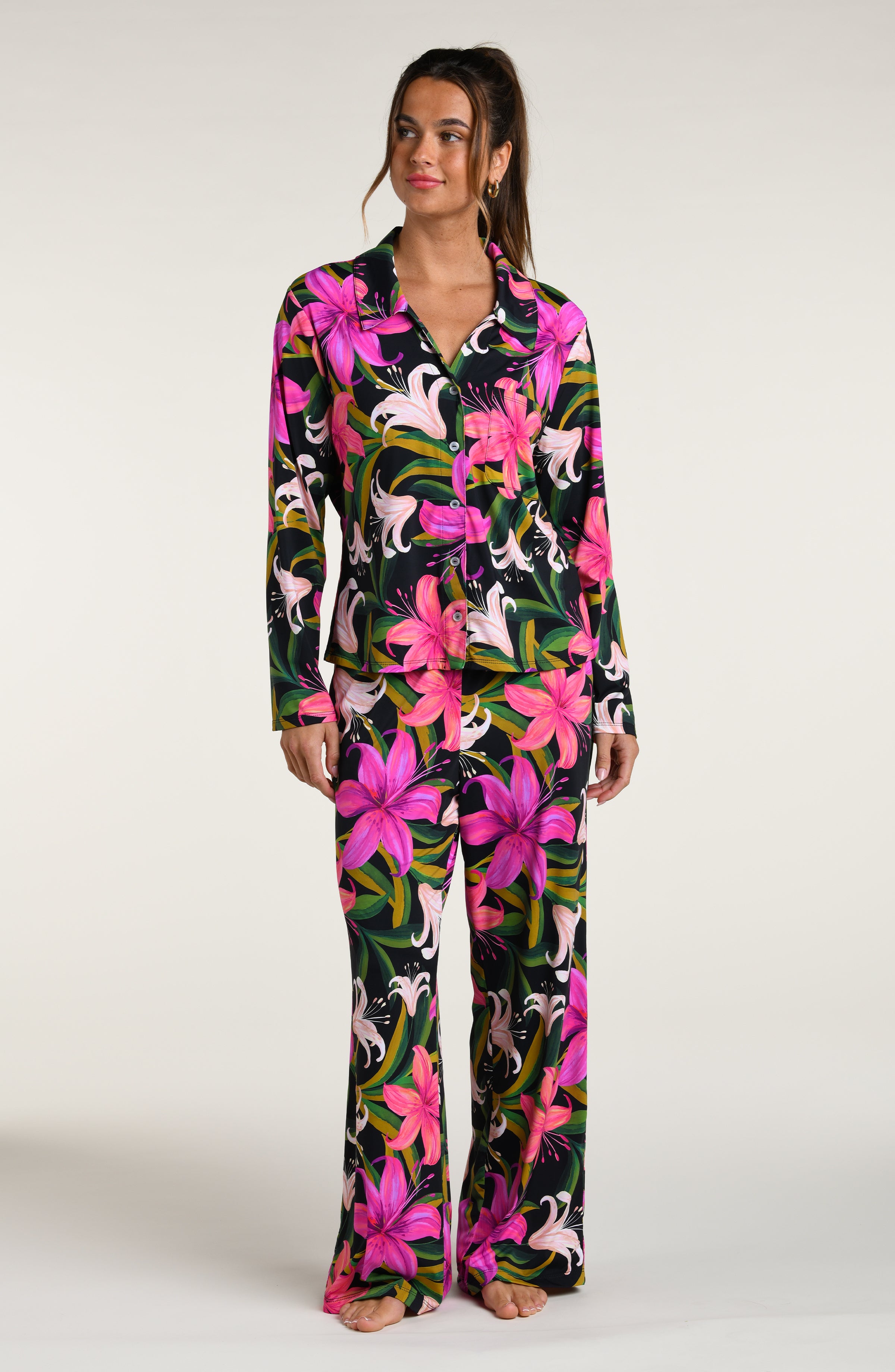 Woman wearing a colorful tropical long sleeve and pant pajama set against a white background.