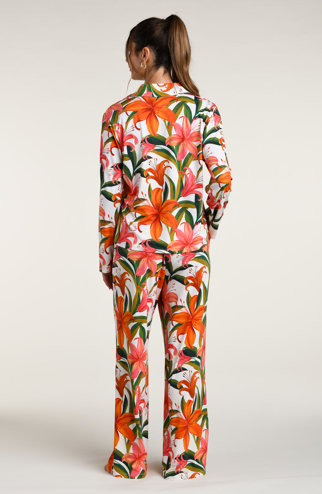 Woman wearing a colorful tropical long sleeve and pant pajama set against a white background.