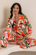 Woman wearing a colorful tropical long sleeve and pant pajama set against a white background.