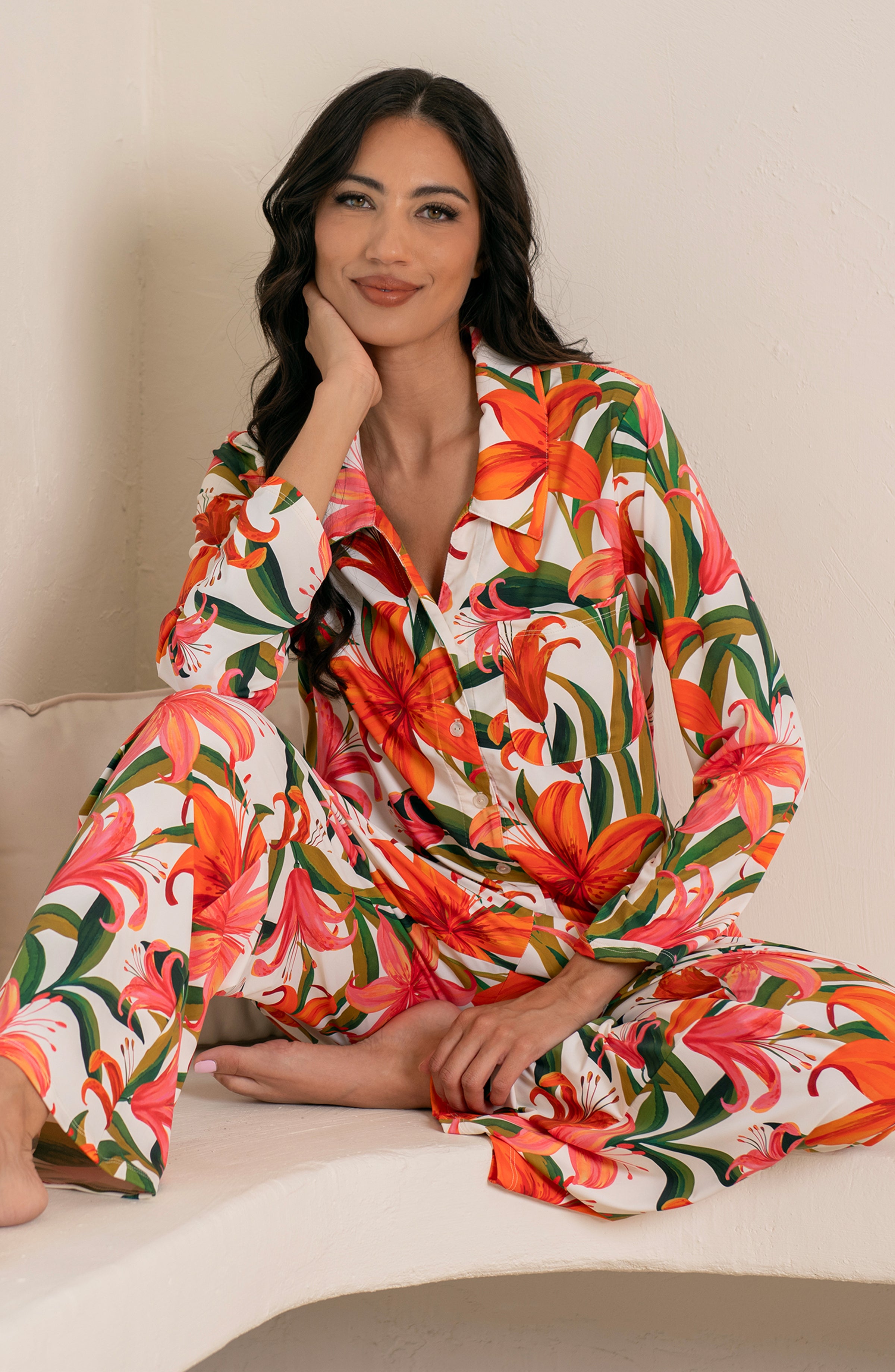 Woman wearing a colorful tropical long sleeve and pant pajama set against a white background.