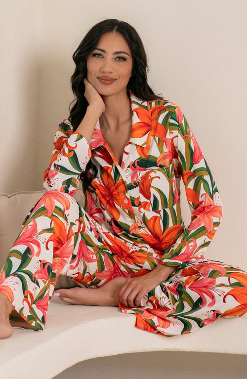 Woman wearing a colorful tropical long sleeve and pant pajama set against a white background.
